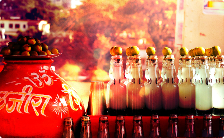 Various clear bottles next to a red pot with black Arabic text that needs to be translated to English.